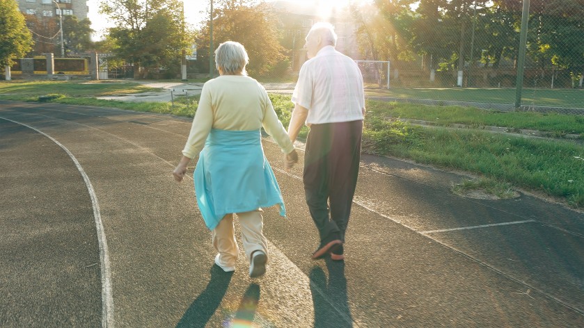 elderly man and woman holding hands on a walk
