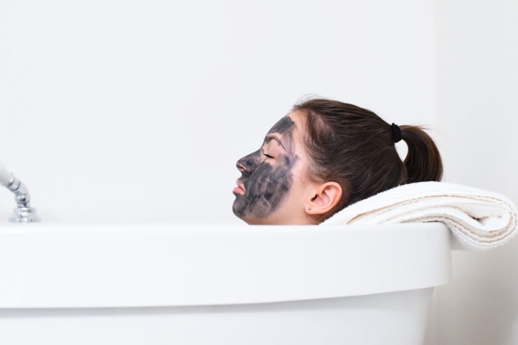 woman relaxing in bathtub with facemark