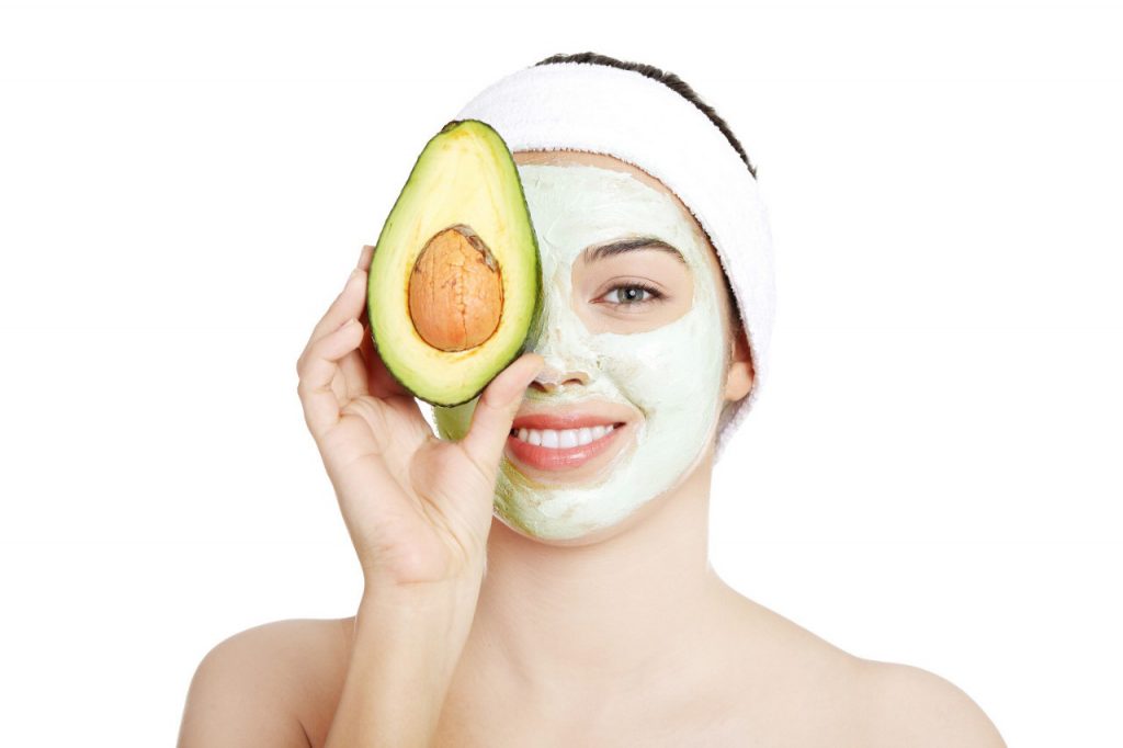 woman with headband and facemark smiling with avocado