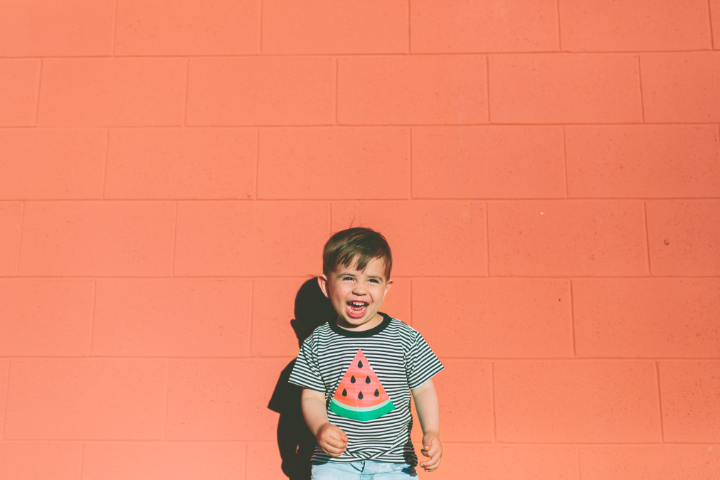young boy laughing in striped watermelon shirt