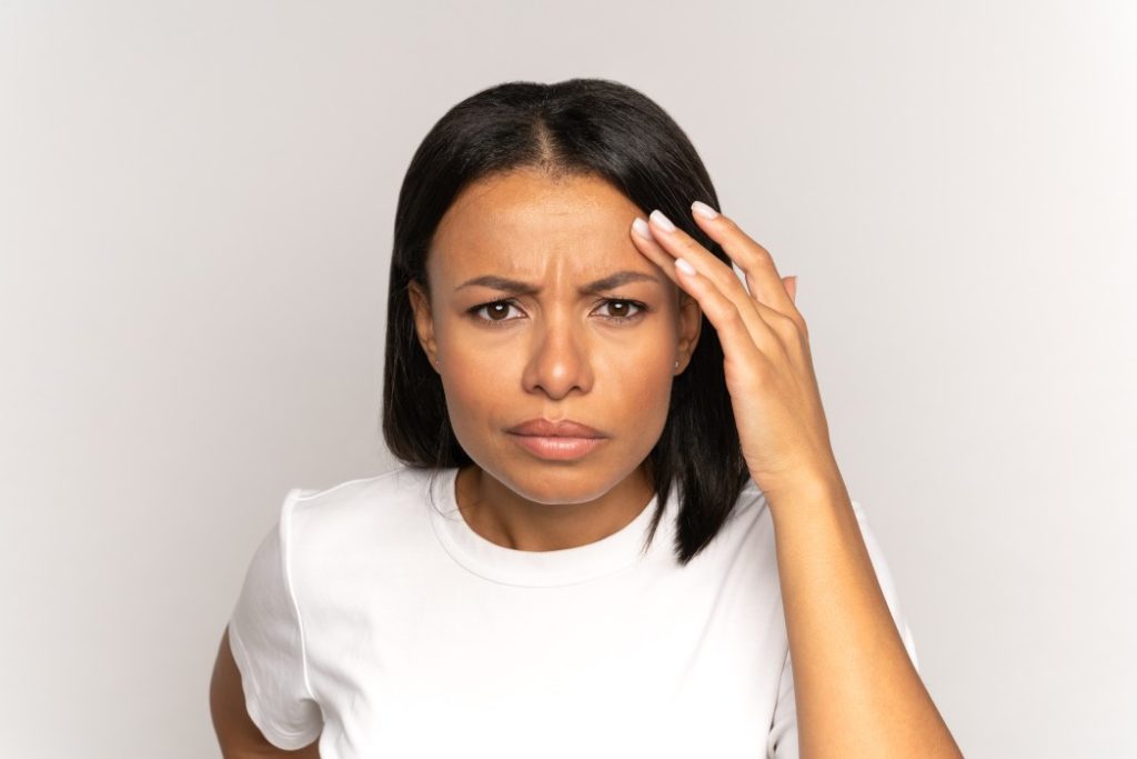 woman with concerned expression touching forehead wrinkles