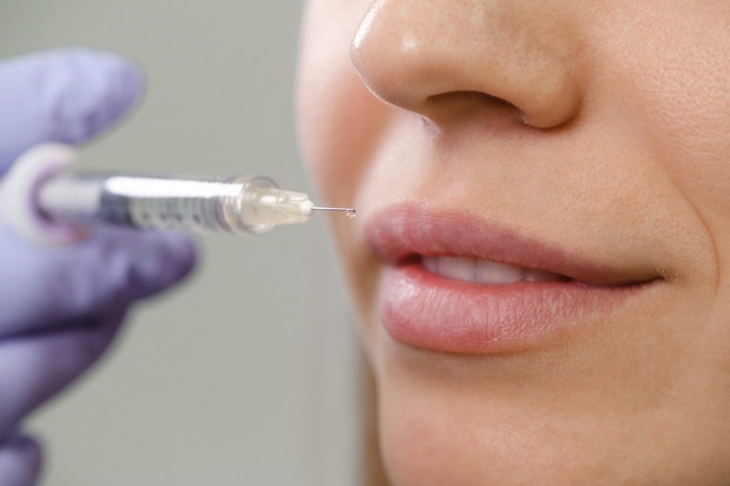 wearing gloves and injecting patient's lips