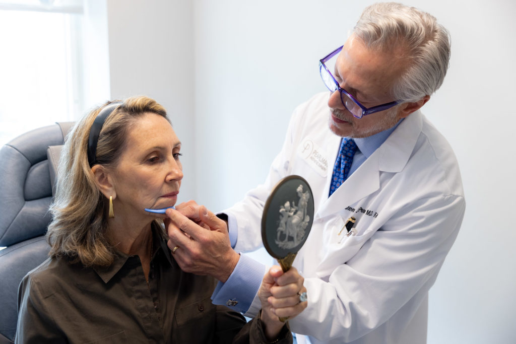 Dr. Pearlman using chin implant tool on woman's face with mirror