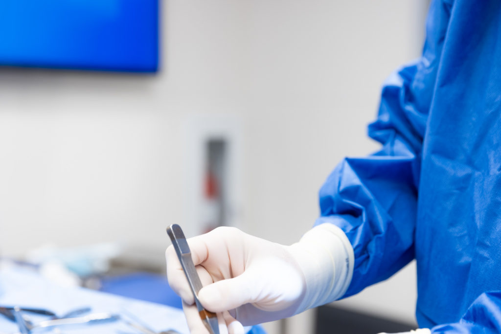 Close-up of a surgeon using medical tweezers while performing puffy nipple surgery in NYC