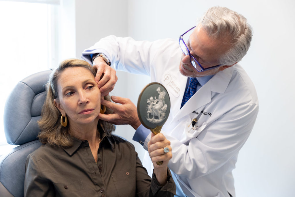 Dr. Pearlman looking at woman's ear with mirror