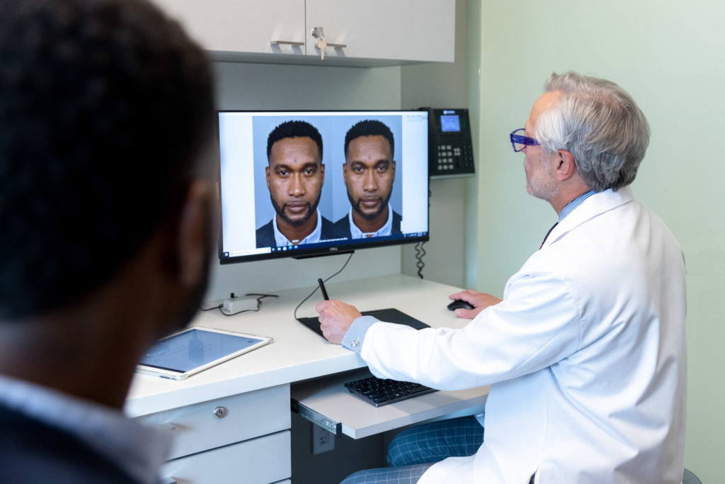 Dr. Pearlman looking at pictures of patient's nose during rhinoplasty consultation