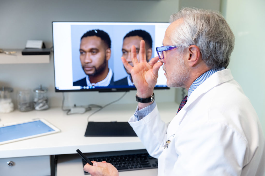 Dr. Pearlman explaining pictures of patient's nose during rhinoplasty consultation