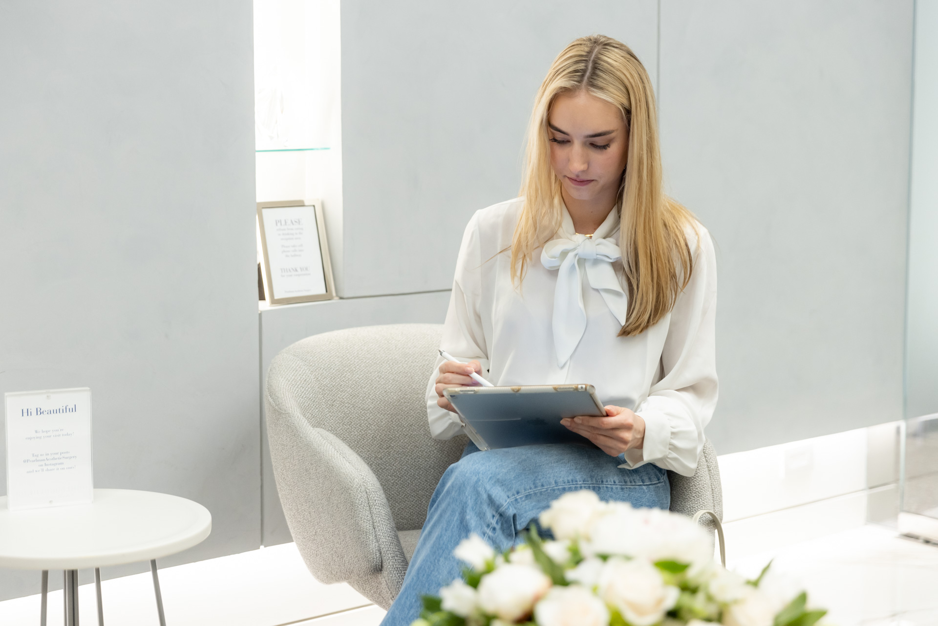woman using iPad in lobby by flowers
