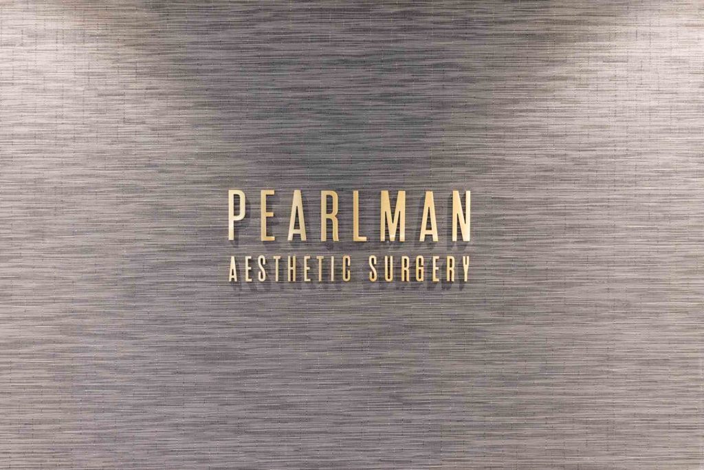 Pearlman Aesthetic Surgery gold sign on gray wall