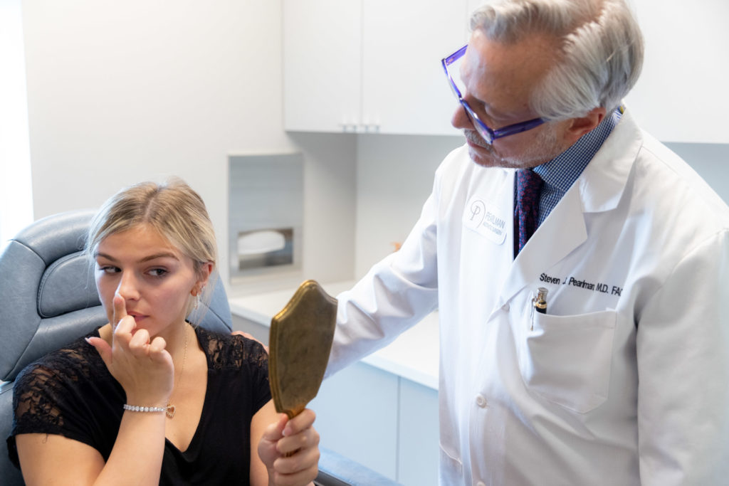 Dr. Pearlman looking at patient's nose in a rhinoplasty consultation
