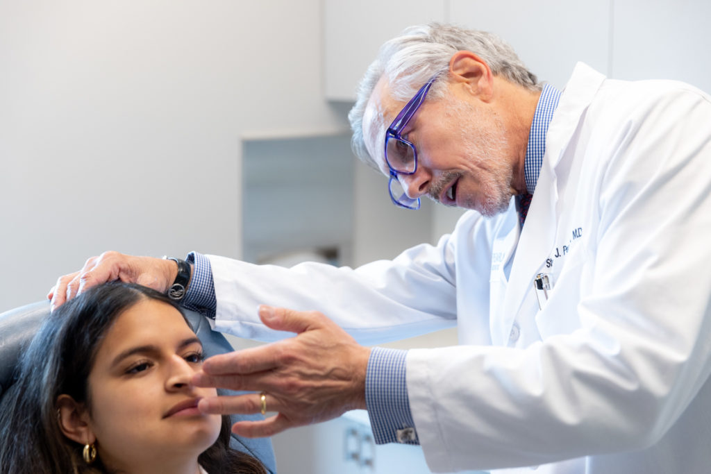 Dr. Pearlman looking at patient's nose during rhinoplasty consultation