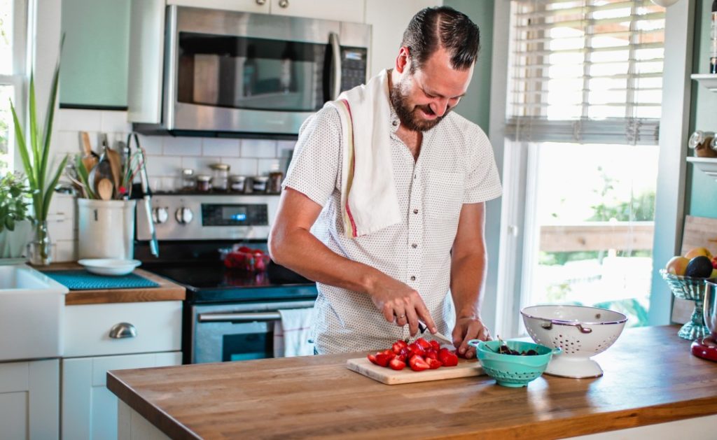 Man cutting up fruit in the kitchen to boost his energy levels