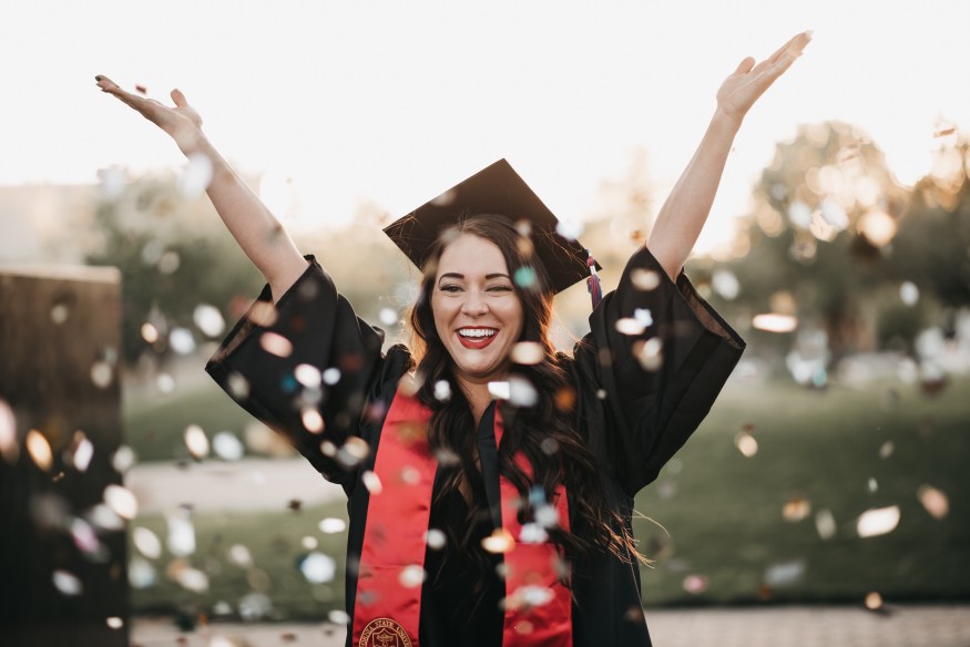 woman in a cap and gown celebrating with confetti