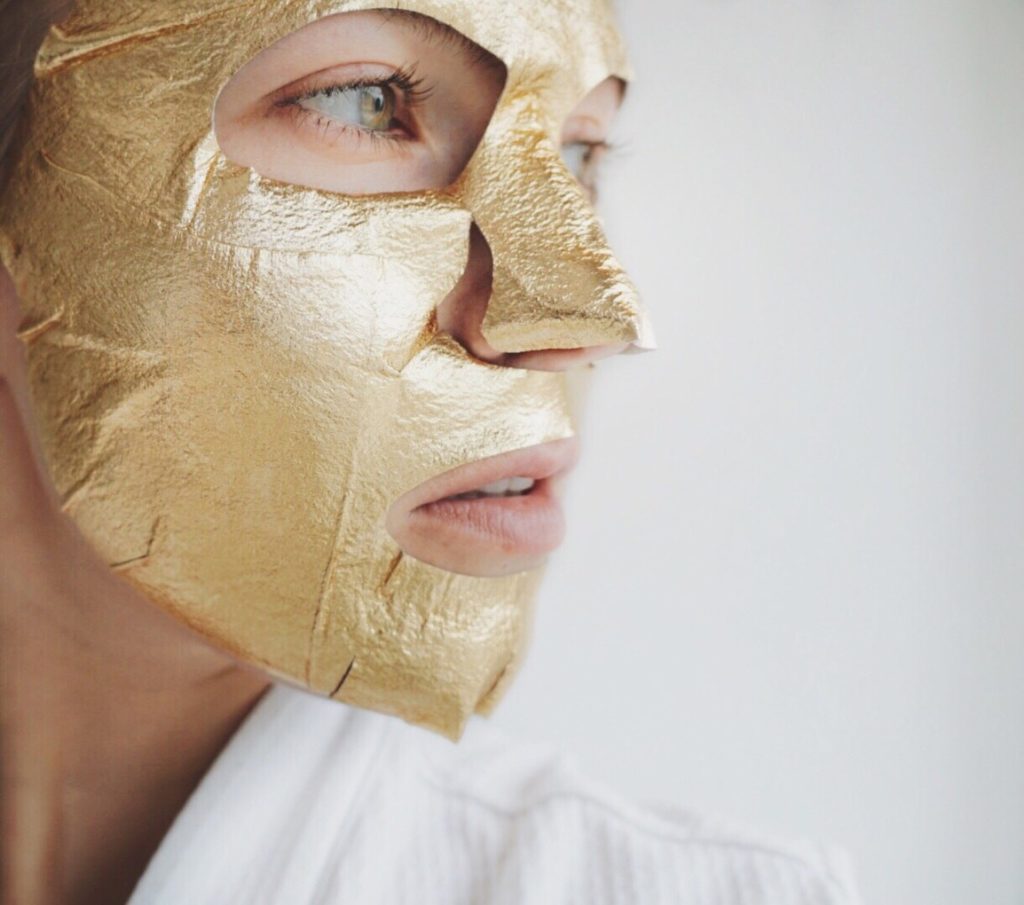 person with gold sheet mask on face