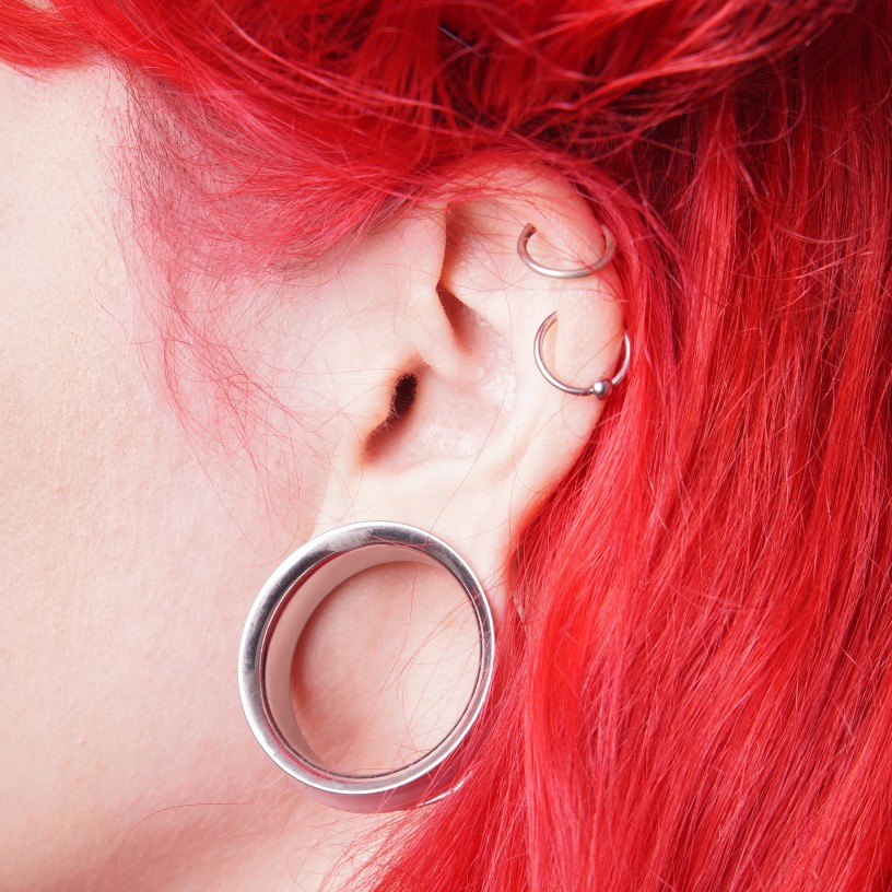 red haired woman's ear piercings and guage