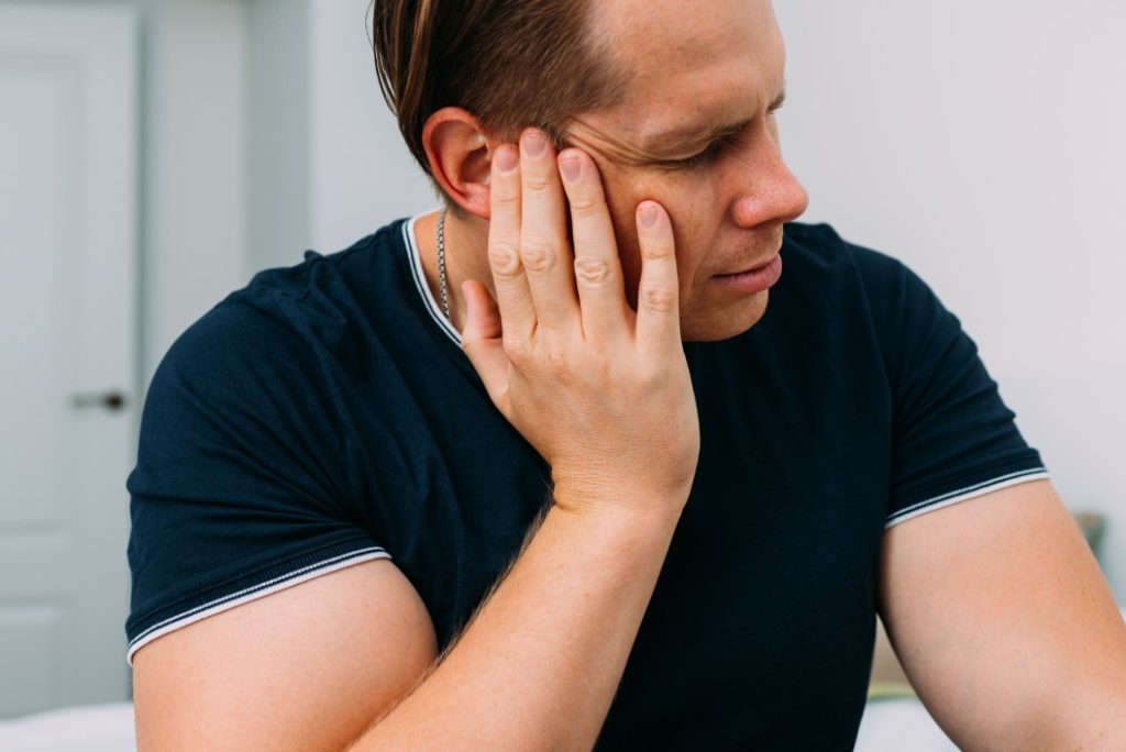 man with large arms touching his cheeks