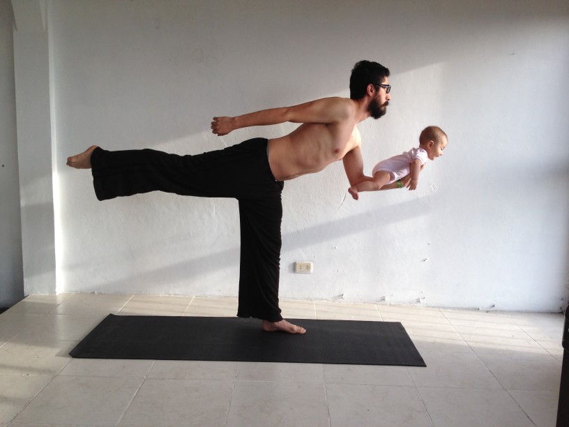 man in sweatpants holding baby while doing yoga
