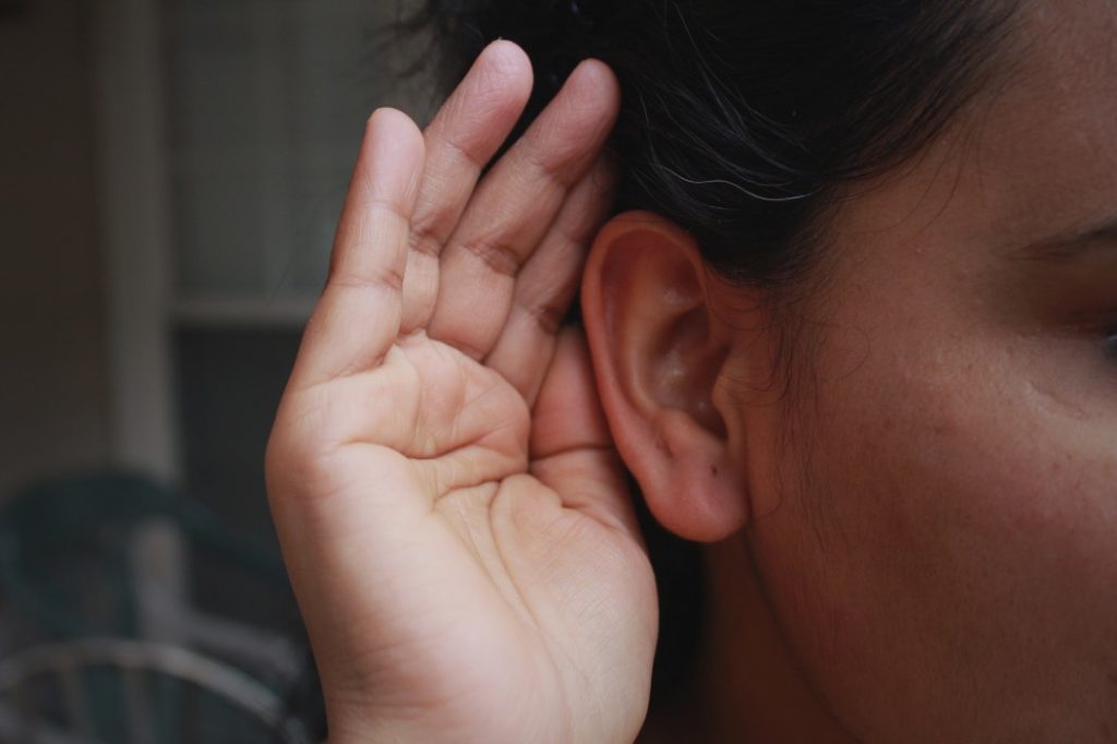 woman holding hand up to her ear to listen