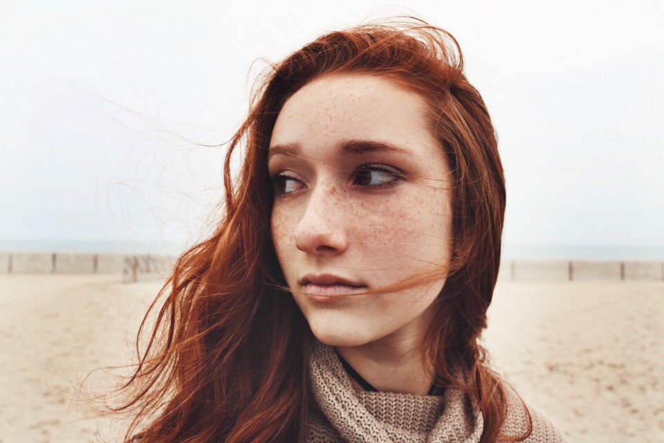red haired woman with freckles in a sweater outside