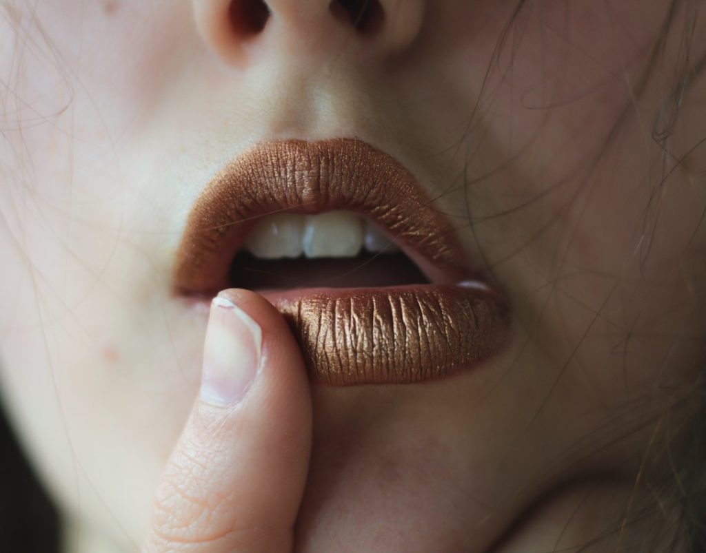 woman touching her metallic lipstick with thumb