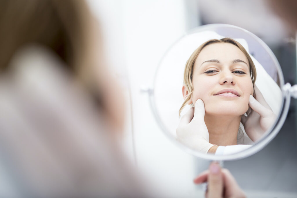 woman having buccal fat examined while looking in mirror