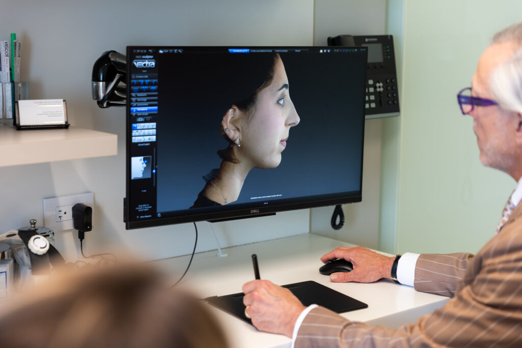 Dr. Pearlman shows a patient their 3D imaging results from a mini rhinoplasty NYC